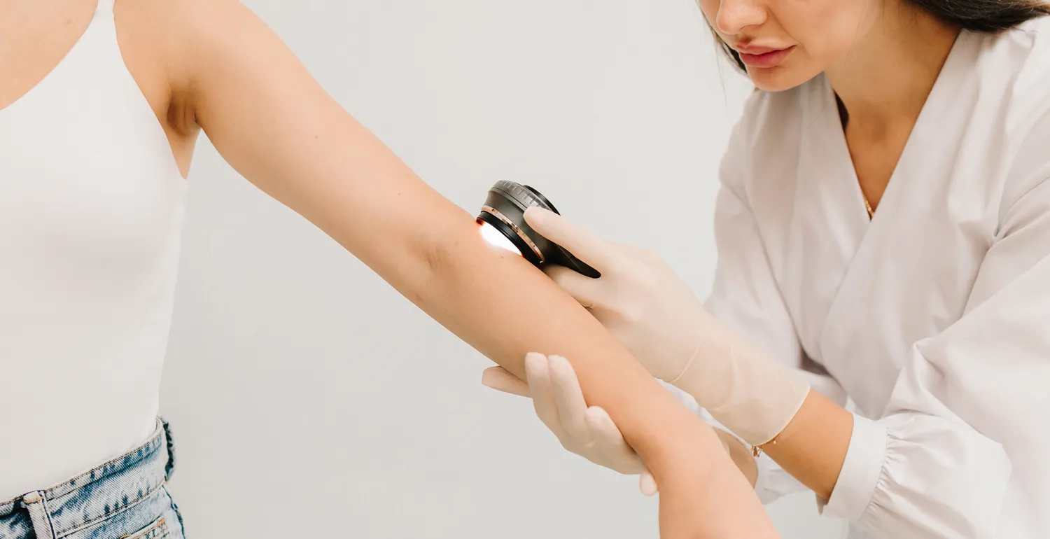 Dermatologist examining girl's skin with dermatoscope